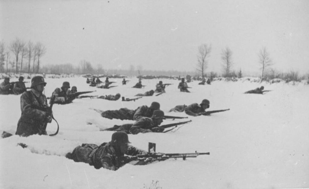 Deutsche Soldaten liegen im Schnee und kämpfen gegen die jugoslawischen Partisanen.