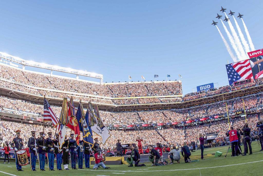 Abschluss der Eröffnungsfeier des Super Bowls 50, am 7. Februar 2016 im Levis Stadium, mit Lady Gaga (Mitte in rot beim Singen der Nationalhymne), den Color Guards der Streitkräfte und einem Flyover der Navy Blue Angels.